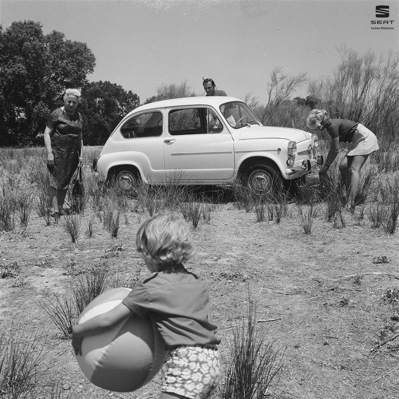 Foto de archivo en blanco y negro: familia junto a un SEAT 600 en el campo