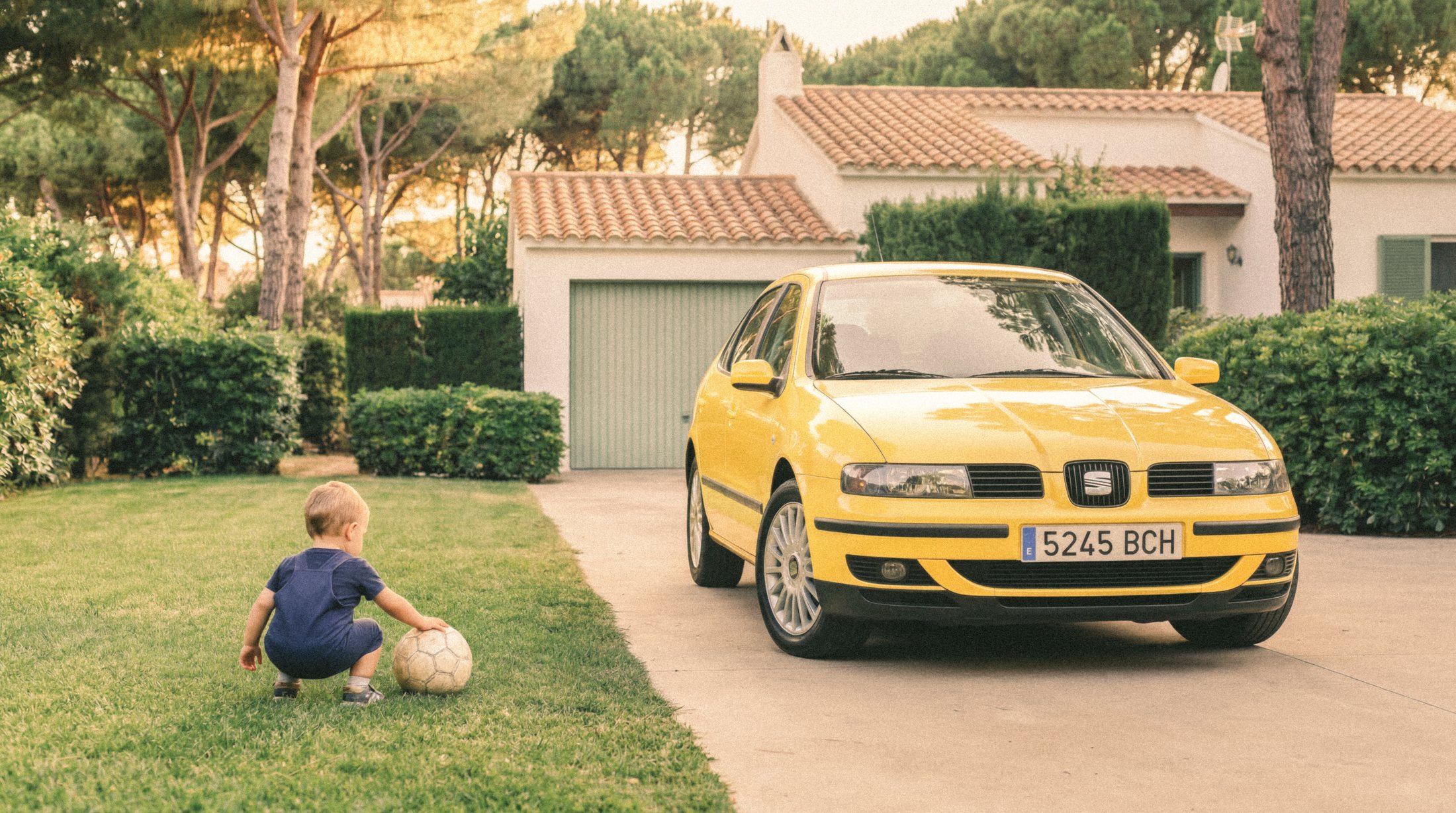 Niño jugando con un balón junto a un SEAT León amarillo
